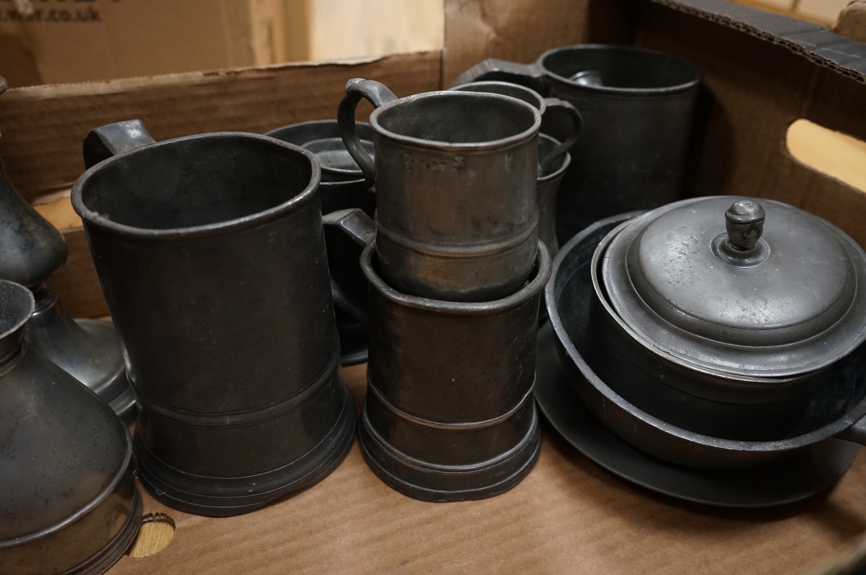 A quantity of pewter to include tankards, dishes and a pair of candlesticks